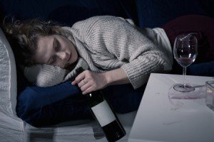 42783612 - tired drunk woman sleeping with bottle of wine